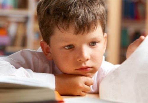 Aluno lendo um livro graças ao impacto da BNCC e alfabetização.