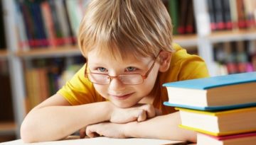 Criança sobre livros após aula. Escola mostrou como incentivar a leitura infantil aos pais.