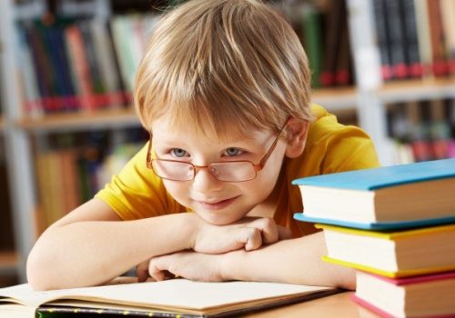 Criança sobre livros após aula. Escola mostrou como incentivar a leitura infantil aos pais.