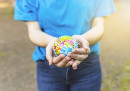 Mulher segura globo nas maos em comemoracao ao dia da ecologia.