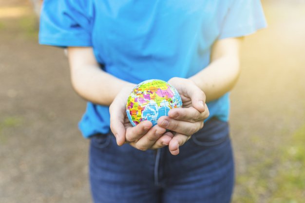 Mulher segura globo nas maos em comemoracao ao dia da ecologia.