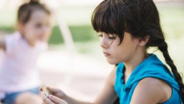 Criança com autismo jogando sozinha no recreio.