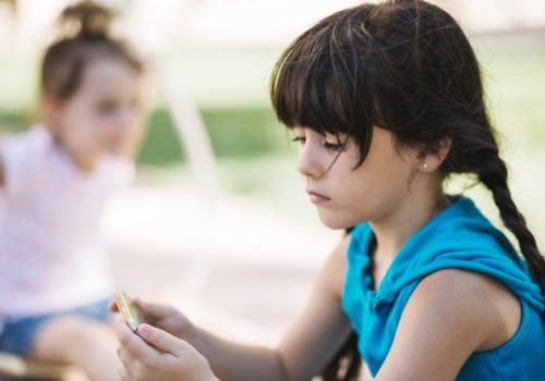 Criança com autismo jogando sozinha no recreio.