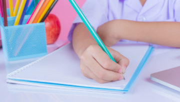 Criança desenvolve uma das atividades de escrita para educação infantil em sala de aula