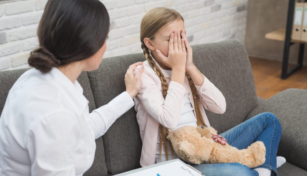 Criança chorando com as mãos no rosto