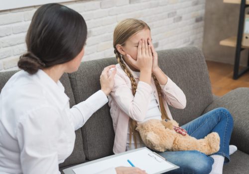 Criança chorando com as mãos no rosto