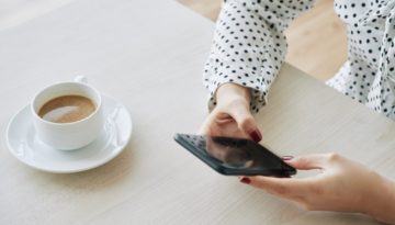 Coordenadora pedagógica lendo novidades de educação no celular e tomando café