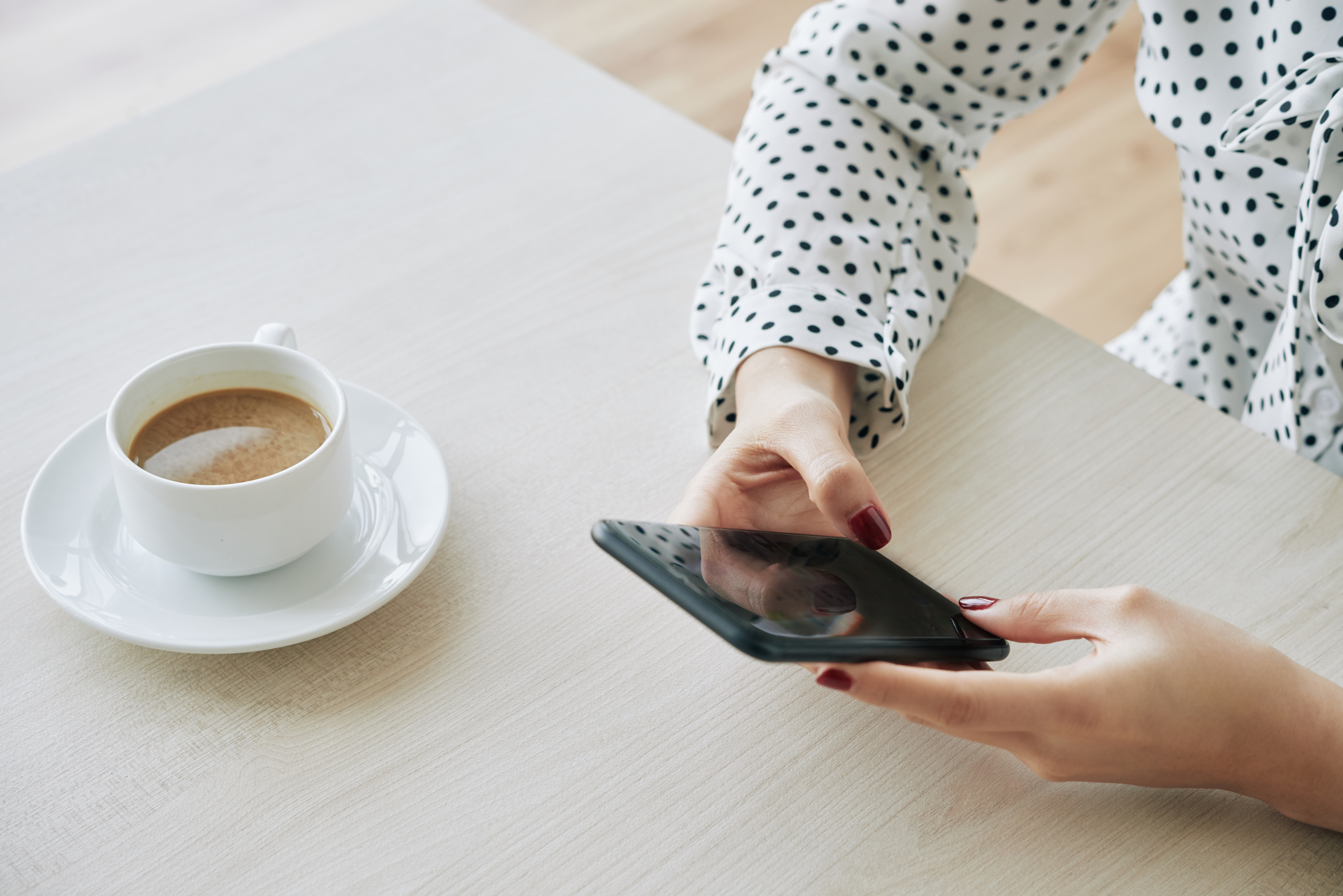 Coordenadora pedagógica lendo novidades de educação no celular e tomando café