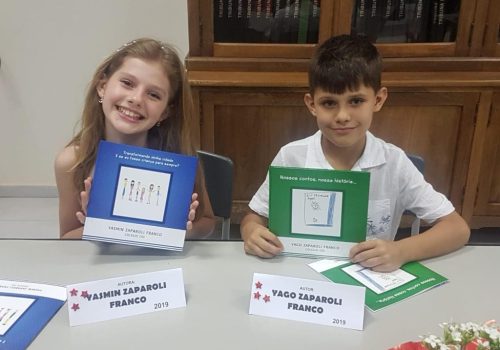 Crianças com os próprios livros sorridentes em Evento de Autógrafos.