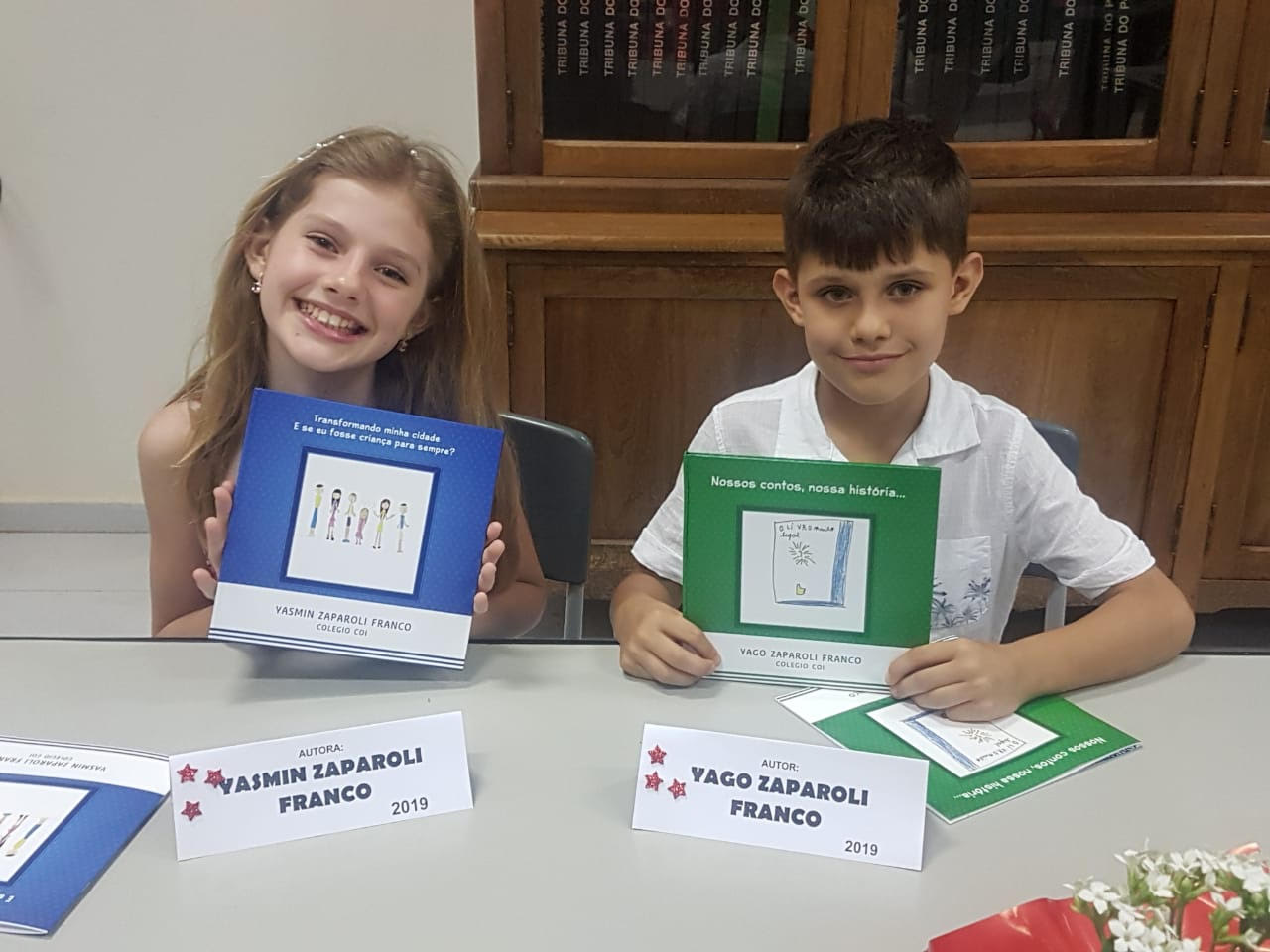 Crianças com os próprios livros sorridentes em Evento de Autógrafos.