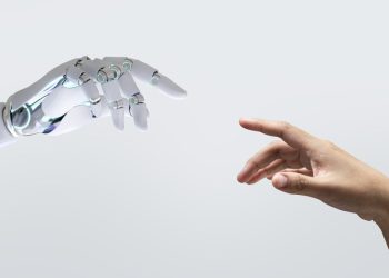 Mão de robô tocando mão humana para ilustrar o debate sobre a inteligência artificial na educação.