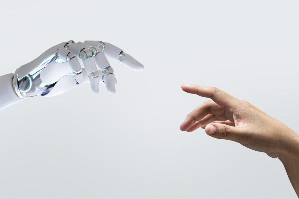 Mão de robô tocando mão humana para ilustrar o debate sobre a inteligência artificial na educação.